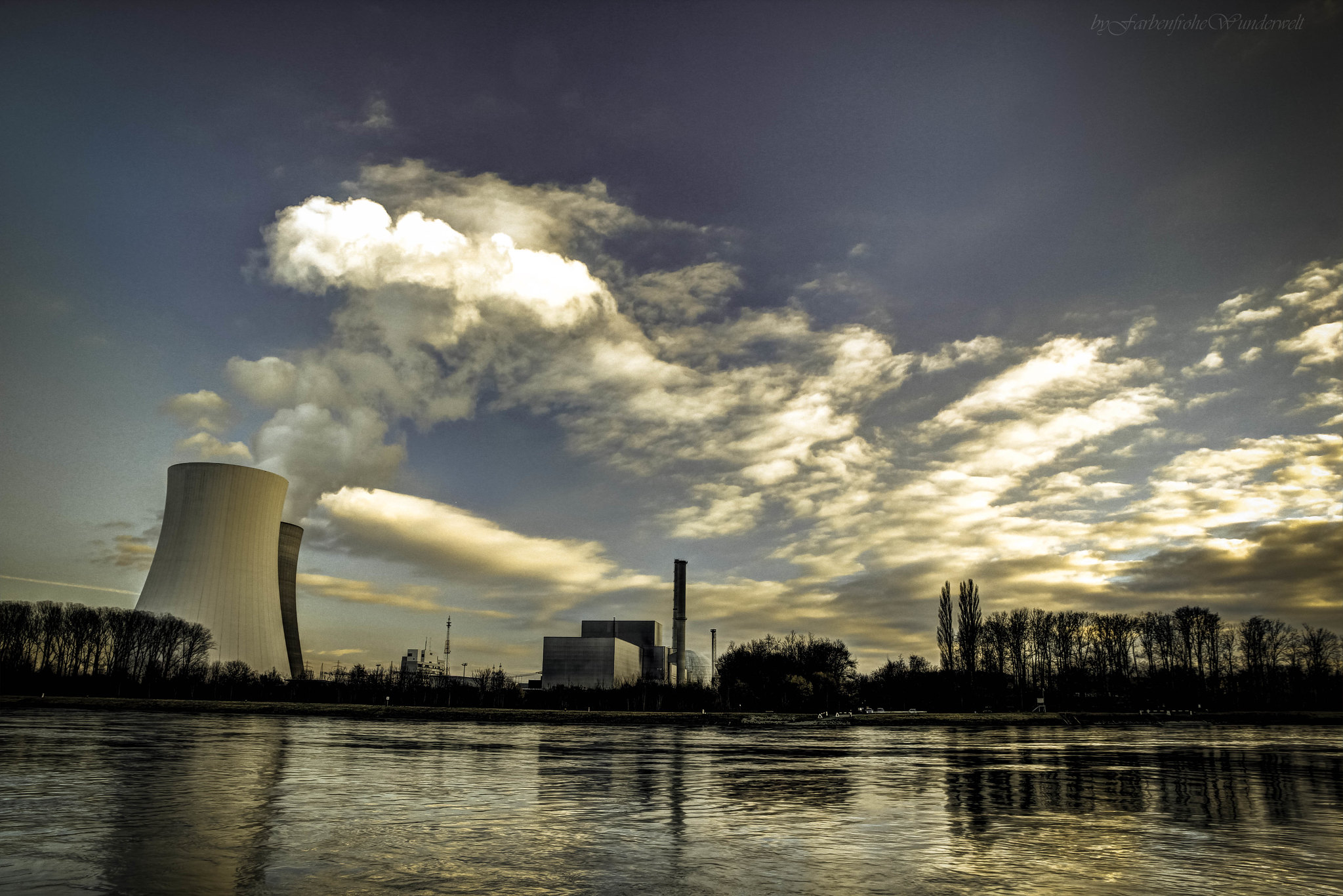 Bild eines Atomkraftwerks aus dessen Kühltürmen Wasserdampf aufsteigt. Das Dampf wird von der Sonne angestrahlt.